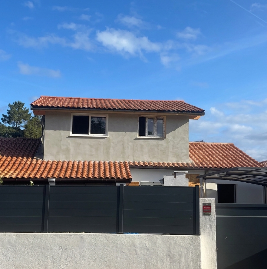 Travaux de ravalement et application de l'enduit de façade sur la surélévation en ossature bois d'une maison à Labenne.